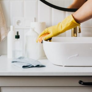 person-in-glove-wiping-surface-of-sink-in-modern-bathroom-4239113
